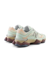 Light green and peach athletic shoes with mesh and leather combined upper, rubber sole, and multi-colored padded midsole design.