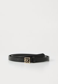 Curea neagră îngustă, cu un model texturat și o cataramă mică de aur în formă de pătrat cu un design geometric, așezată pe o suprafață albă.