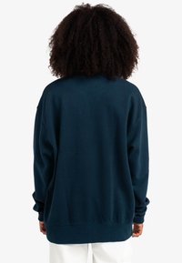 Sudadera over-size blu navy in tessuto morbido, con scollatura rotonda e polsini a coste, orlo dritto e senza grafiche visibili.