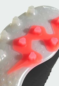 Svart fotbollssko sula med genomskinlig gummi och vita samt rosa dobbar, texturerad yta och en distinkt form för grepp.