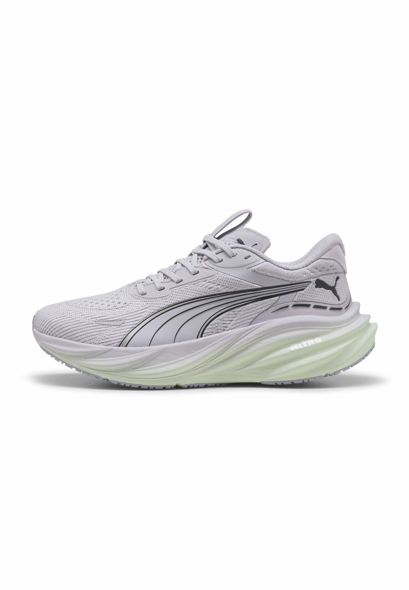 Zapatilla deportiva de color gris claro con parte superior de malla texturizada, detalles en negro y una suela gruesa y acolchada de color verde. Presenta un diseño de cordones y talón moldeado.