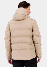 Chaqueta de plumas beige con capucha, con textura acolchada, puños elásticos y un detalle de logo en el hombro, diseñada para brindar calidez y comodidad.