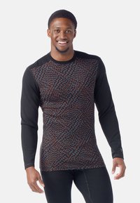 Camicia a maniche lunghe con corpo a motivo in rosso e blu su sfondo nero e maniche nere unite. Tessuto morbido e strutturato.