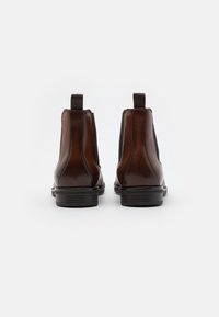 Bottes basses en cuir marron avec panneaux latéraux élastiques, bout arrondi et petit talon empilé. Languette arrière pour un port facile.