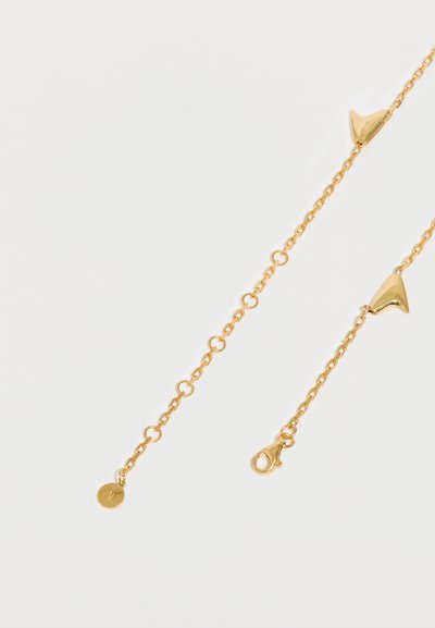 Delikāts zelta ķēdes kaklarota ar mazu apaļu birku un abstraktiem trijstūra formas zelta kuloniem, attēlota uz balta fona.