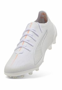 Valkoinen jalkapallokenkä, jossa on teksturoitu pinta, oranssit yksityiskohdat, metallinen logo ja kuusi läpinäkyvää nappulaa pidon varmistamiseksi. Naruja kulkee edessä.