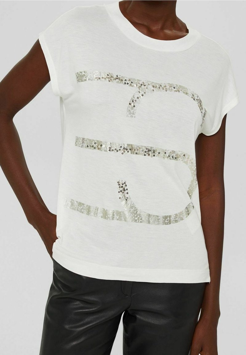 Weißes kurzärmliges T-Shirt mit einem strukturierten silbernen Pailletten-Graphic-Design auf der Brust, ergänzt durch einen weichen Stoff und eine lockere Passform.
