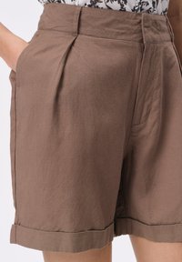 Brązowe bawełniane szorty z wysokim stanem, fałdami, bocznymi kieszeniami i podwiniętymi brzegami, charakteryzujące się gładką fakturą i casualowym stylem.