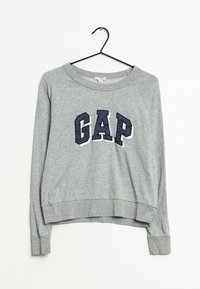 Šedá mikina s kulatým výstřihem, žebrovanými manžetami a zkráceným lemem. Na přední straně se nachází nápis "GAP" v námořnické modré.