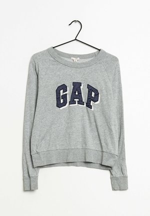 Felpa grigia con scollo rotondo, polsini a costine e orlo corto. Presenta la parola "GAP" in blu navy sul davanti.
