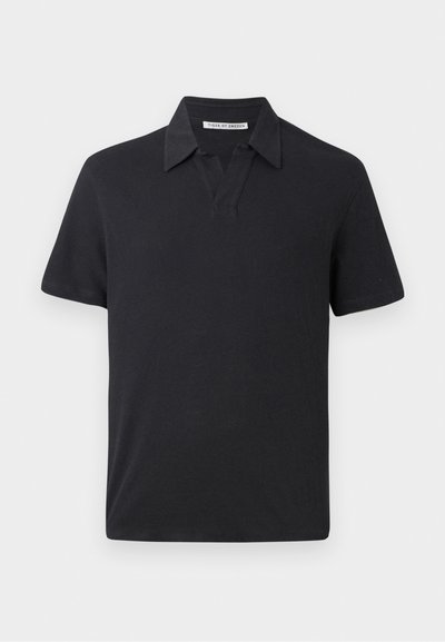 Μαύρο πόλο μπλουζάκι φτιαγμένο από βαμβάκι, με κοντό γιακά, κοντά μανίκια και άνετη εφαρμογή. Απλός σχεδιασμός, χωρίς ορατά μοτίβα ή διακοσμητικά.