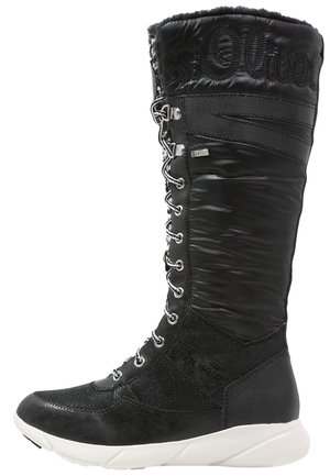 Bota alta negra de invierno con cordones en la parte delantera, parte superior texturizada y suela gruesa blanca.