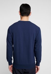 Mikina navy modré barvy s kulatým výstřihem vyrobená z bavlněné směsi, s dlouhými rukávy, pružným zakončením a hladkým povrchem. Žádné viditelné loga.