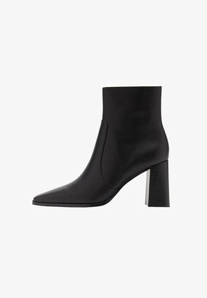 Botte cheville en cuir noir avec un bout pointu et un talon bloc moyen. Texture lisse avec un design courbé simple et sans ornements visibles.