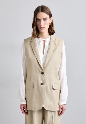 Gilet en lin beige avec une silhouette ajustée, doté d'un col cranté, de deux poches avant et de deux boutons foncés.
