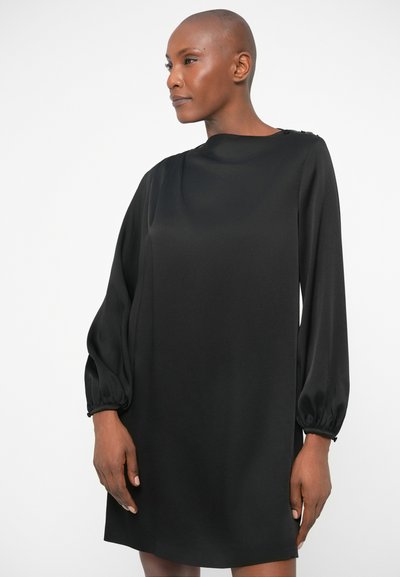 Rochie neagră cu mânecă lungă, dintr-un material fin. Prezintă un guler înalt și mâneci tip balon cu manșete strânse. Croială scurtă, lejeră.