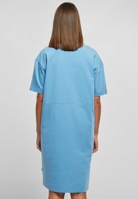 Niebieska bawełniana sukienka t-shirtowa z krótkim rękawem, luźny krój i okrągły dół. Posiada poziomą szew z tyłu, gładka tekstura.