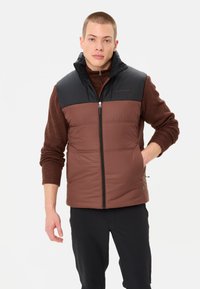 Braune Steppweste mit einem schwarzen, isolierten oberen Abschnitt. Verfügt über einen Frontreißverschluss, Seiten Taschen und einen hohen Kragen für zusätzliche Wärme.