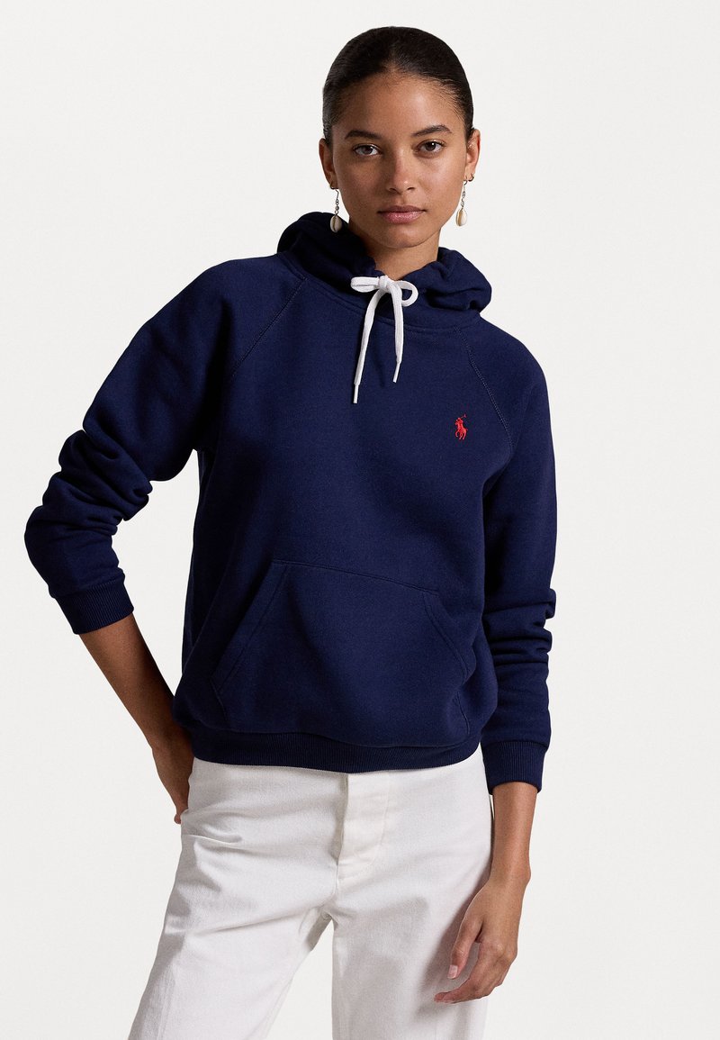 Donkerblauwe hoodie van zacht materiaal met een kangoeroezak, uitgerust met een witte trekkoort en een klein rood geborduurd logo op de borst.