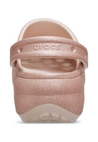 Sabots Crocs métalliques roses avec un bout large et arrondi, un dessus texturé et une sangle au talon ajustable. Légers et faciles à nettoyer.