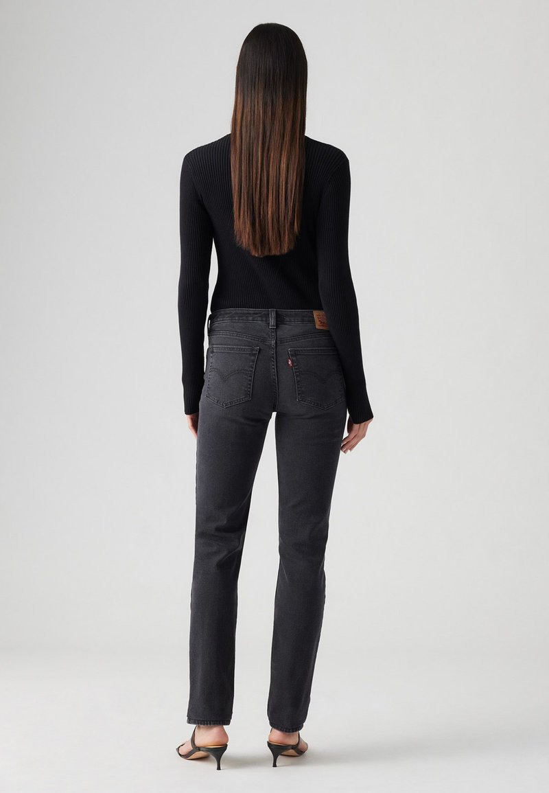 Jean skinny noir taille haute, avec un patch en cuir à l'arrière, et un tissu lisse et texturé. Coupe slim et jambes droites.