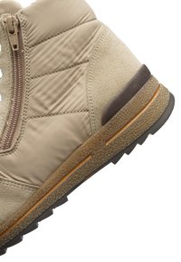 Beiger Winterstiefel mit gestepptem Stoff, Wildlederakzenten, seitlichem Reißverschluss und strukturierter Gummisohle mit Profil.