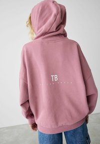Felpa con cappuccio oversize in rosa polveroso, caratterizzata da una finitura testurizzata e un logo stampato bianco "TB by Ted Baker" sul retro.