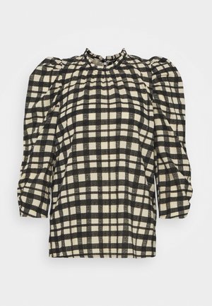 Blouse à manches longues à carreaux noir et blanc avec épaules bouffantes et un col montant à volants.