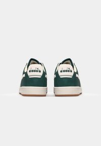 Green suede sneakers with white accents, round heel, textured gum sole, and logo detail on the back. Simple, classic silhouette.