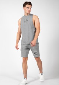Grijze mouwloze top met logo en grijze shorts. Katoenmengsel, relaxte pasvorm, soepele textuur, gecombineerd met witte sneakers.