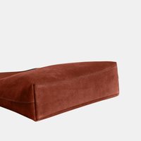 Base rectangulaire de sac à main en daim marron avec des coutures visibles sur un fond uni gris clair.