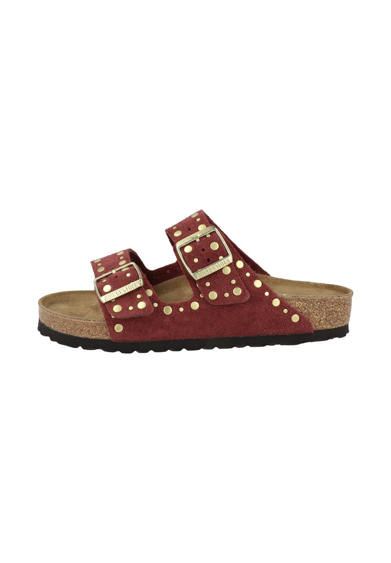 Rode suède slide-sandaal met twee verstelbare banden, gouden studs en een getextureerde kurken voetbed. Zwarte rubberen buitenzool.