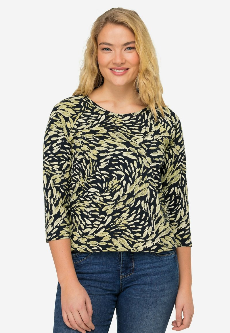 Zwarte shirt met een bladerenpatroon in lichtgroen, met een ronde halslijn en driekwart mouwen. Zacht materiaal met een relaxte pasvorm.