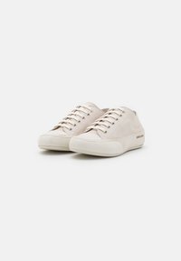 Baskets en toile beige avec surface texturée, bout rond, semelle en caoutchouc blanche et œillets en métal pour les lacets, présentant un branding subtil sur le côté.