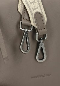 Bolso de piel gris con una superficie texturizada, que presenta ganchos de snaps metálicos y una correa tejida de contraste con acentos de color claro. Logotipo grabado en la parte delantera.