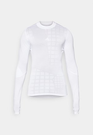 Hosszú ujjú sportpóló fehér színben, rácsos mintázattal és texturált részletekkel. Simább, rugalmas anyagból készült, testhezálló fazonnal.