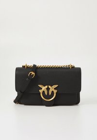 Svart skulderveske i teksturert skinn med gullkjede som stropp og gullspenne som har to fugler vendt mot hverandre på en ring.