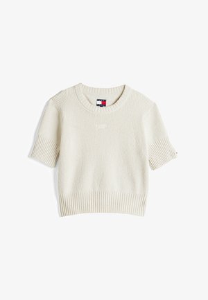 Kremowy sweter z krótkim rękawem, o prążkowanej fakturze, okrągłym dekolcie oraz subtelnym logo Tommy Jeans. Posiada prosty dół i szerokie rękawy.