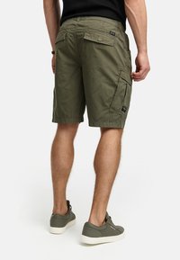 Shorts cargo verts olive fabriqués en tissu léger, avec plusieurs poches et une coupe décontractée, vus de l'arrière.