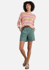 Striped knit sweater in pink, orange, and yellow hues, paired with green shorts; features a relaxed fit, pockets, and a braided belt.