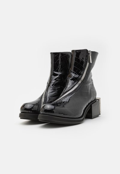 Black patent leather ankle boots with reptile texture, diagonal zipper, and a chunky block heel. Notable hardware accent on heel.