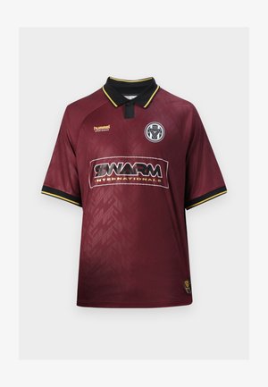 Luumuinen urheilupaita mustilla ja keltaisilla kauluksilla ja kalvosimilla, "SWARM INTERNATIONALS" logo keskellä, hummel-logo yläoikealla, joukkueen vaakuna ylävasemmalla.