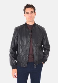 Giubbotto bomber in pelle nera con colletto e polsini a coste, caratterizzato da chiusura con zip, tasche laterali e una finitura testurizzata.
