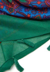 Multikleurige sjaal met een blauw ontwerp met bloemmotieven en een effen groene onderkant. Inclusief decoratieve kwastjes aan de randen.