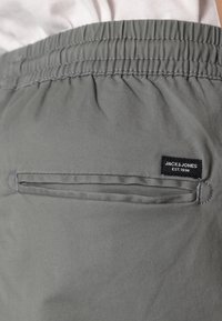 Grå lätta shorts med elastisk midja, med en bakficka och en svart etikett med "JACK & JONES EST. 1990."