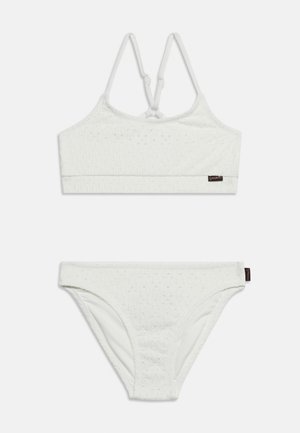 Valge tekstuuriga kahepüksiline bikiinikomplekt peenikeste reguleeritavate õlapaeladega ülaosas ja sobivate madala vöökohaga pükstega, mõlemal väikesed mustad brändi sildid.