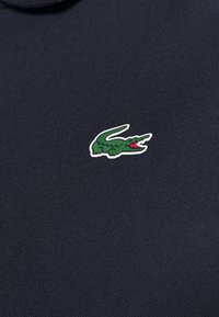 Polo en color navy con un pequeño logo de cocodrilo verde y colorido en el área del pecho izquierdo, confeccionado en una suave mezcla de algodón.