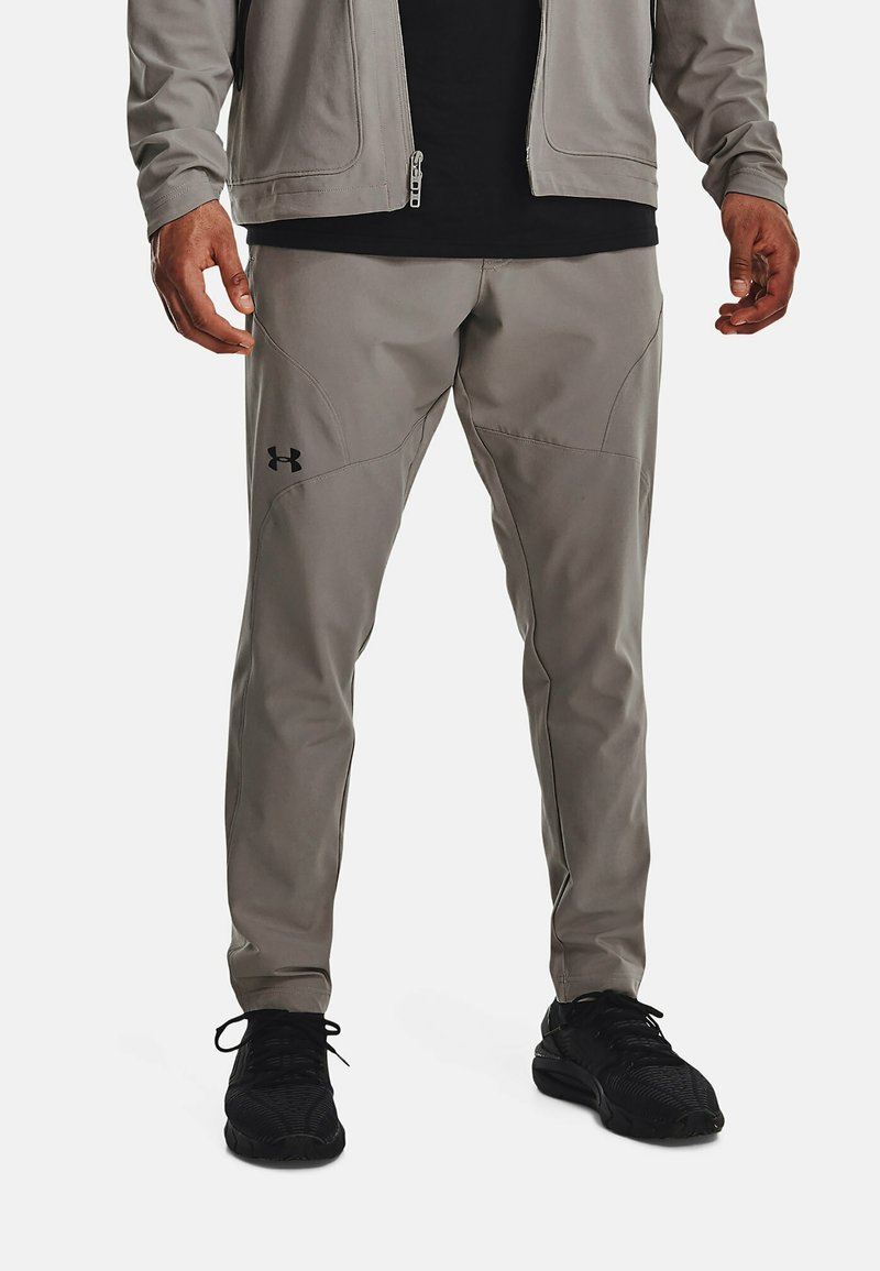 Grå träningbyxor med smal passform, med svarta sömmar och detaljer, samt en Under Armour-logotyp på vänster lår.