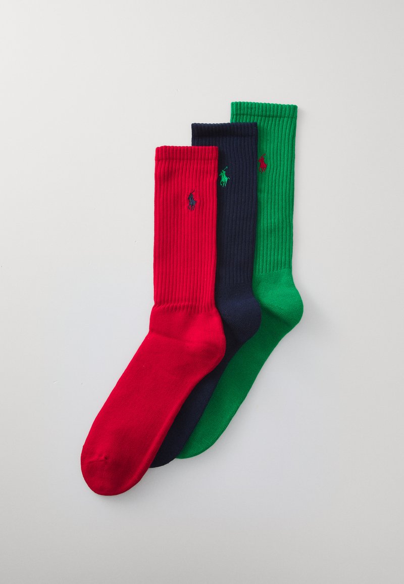 Trois paires de chaussettes côtelées en rouge, bleu marine et vert. Chaque paire présente un petit logo brodé. Elles ont une longueur mi-mollet et une texture lisse.