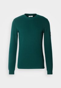 Zielona koszula z długim rękawem wykonana z bawełny o fakturze. Posiada okrągły dekolt, prążkowane mankiety oraz małą naszywkę z logo na lewym rękawie.